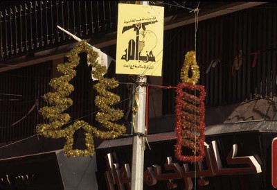 Christmas ornaments on either side of the Hezbollah flag, circa 1995. Phot. Norbert Schilletr